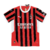 Nova camisa titular do AC Milan 24/25: listras vermelhas e pretas em tom sobre tom, gola e punhos brancos. Escudo e logo PUMA em branco. Costas vermelhas com selo dos 125 anos.