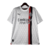 Camisa reserva do Milan 23/24 é branca com duas listras verticais em vermelho e preto. Detalhes em prata por toda camisa. Escudo e logos puma prateados.