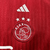 A camisa do Ajax tem design branco com uma larga faixa vermelha na vertical, que se estende nas laterais, mangas, gola e punhos. O escudo fica abaixo do logo da Adidas no centro do peito. Três cruzes de Santo André na nuca.