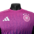 A nova camisa reserva da Alemanha apresenta degradê em rosa e roxo, inspirado na águia, com detalhes rosados na gola, ombros e recortes curvos. Logos Adidas e DFB em rosa.