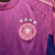 A nova camisa reserva da Alemanha apresenta degradê em rosa e roxo, inspirado na águia, com detalhes rosados na gola, ombros e recortes curvos. Logos Adidas e DFB em rosa.