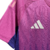 A nova camisa reserva da Alemanha apresenta degradê em rosa e roxo, inspirado na águia, com detalhes rosados na gola, ombros e recortes curvos. Logos Adidas e DFB em rosa.