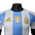 A nova camisa titular da Argentina destaca o branco com três listras verticais azul celeste. Detalhes azuis estão presentes nas mangas, gola. Logos Adidas e AFA em dourado e o patch de campeã mundial no peito.