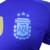 O manto reserva da Argentina destaca o azul royal, homenageando Maradona. As listras celestes nos ombros representam a bandeira. Logos Adidas e AFA em celeste, com o patch de campeã mundial no peito.