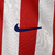 Camisa manga longa titular do Atlético de Madrid adota um design clássico, com listras vermelhas e brancas na frente. Escudo Atletico de Madrid e logo da Nike bordados. A bandeira da Espanha é vista na nuca.