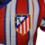 A nova camisa titular do Atlético de Madrid tem listras vermelhas e brancas, separadas por linhas azuis borradas. A gola é mini-polo azul e os punhos vermelhos. O escudo antigo retorna. Logos Nike e Riyadh Air são azuis.