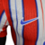 A nova camisa titular do Atlético de Madrid tem listras vermelhas e brancas, separadas por linhas azuis borradas. A gola é mini-polo azul e os punhos vermelhos. O escudo antigo retorna. Logos Nike e Riyadh Air são azuis.