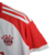 A camisa titular do Bayern de Munique 2023-2024 é branca com gola redonda vermelha. Escudo, logo da Adidas e patrocínio máster em vermelho. Três listras nos ombros em branco. Inscrições dentro da gola e na nuca em vermelho.