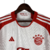 Camisa titular manga longa do Bayern de Munique 2023-2024 é branca com gola redonda vermelha. Escudo e logo da Adidas em vermelho. Inscrições dentro da gola e na nuca em vermelho.