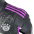 Camisa reserva Bayern Munique: preta, diamonds verde e violeta formam mapa mundi. Três listras, faixas e dorsais violeta. 'MIA SAN MIA' na nuca em verde. Escudo e logo Adidas monocromáticos.