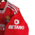 A camisa titular do Benfica é vermelha, com gola V branca e detalhe vermelho com borda branca. Listras brancas nos ombros, douradas nas laterais e barra. Escudo do Benfica no lado esquerdo, logo da Adidas em branco no lado direito.