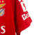 A nova camisa titular do Benfica tem chevrons em relevo vermelho encarnado na frente. Gola V branca com nuca vermelha, mangas vermelhas com três listras brancas nos ombros. Escudo e logo Adidas em branco.