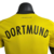 Nova camisa titular do BVB: parte superior amarela e inferior preta, com desenho da "Muralha Amarela". Escudo Borussia Dortmund e logo Puma bordado. Selo "Design datt Ding" na gola e hashtag #BorussiaVerbindet na nuca.