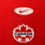 Camisa titular do Canadá para a Copa América 2024 vermelha com faixa lateral grená. Gola redonda metade vermelha, metade branca. Punhos vermelhos com faixa branca. Swoosh Nike em elipse branca, escudo da Federação Canadense abaixo.