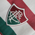 Camisa reserva do Fluminense: cor branca com faixas horizontais grená e verde, escudo do clube no lado esquerdo e logo da fornecedora no lado direito. Homenagem à Copa Rio de 1952 e grafismos estilizados nas mangas. Patch campeão da Libertadores 2023.