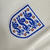 Camisa titular da seleção inglesa feminina com detalhes em azul inspirada em tijolos brancos de Wembley em 1923 e na seleção feminina inglesa de 1984. Escudo da Federação Inglesa à esquerda, logo Nike azul à direita.