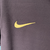 Manto reserva da seleção inglesa com roxo predominante e faixas laterais multicoloridas. Swoosh Nike dourado à direita, Three Lions roxo e dourado à esquerda. Inspirada na camisa reserva da Inglaterra para a Euro 2024.