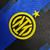 Camisa titular Inter de Milão 2023-2024: Azul com três listras verticais pretas estilo "glitch". Detalhes pretos nos ombros e punhos, gola redonda azul com bandeiras de Milão e Inter. Logo Nike em amarelo, escudo Inter amarelo no lado esquerdo.