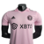 Camisa titular rosa do Inter Miami, chamada "Heartbeat Kit", com gola polo e listras pretas nos ombros. Mangas rosa com punhos com batimentos cardíacos em relevo. Escudo Inter Miami e logo Adidas e em preto.