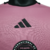 A camisa titular 24/25 rosa do Inter Miami, 'Easy Pink', traz faixas e detalhes pretos, com escudo, logo da Adidas e Royal Caribbean em preto. A frase 'Liberdade para Sonhar' na nuca e barra complementa o design.