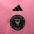 A camisa rosa do Inter Miami, 'Easy Pink', traz faixas e detalhes pretos, com escudo, logo da Adidas e Royal Caribbean em preto. A frase 'Liberdade para Sonhar' na nuca e barra complementa o design.