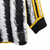 Camisa manga longa titular da Juventus 23/24 tem listras verticais estilizadas lembrando pelos de zebra. Gola preta com contorno amarelo, punhos no mesmo padrão. Logo Adidas e da Juventus em amarelo.