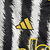 Camisa manga longa titular da Juventus 23/24 tem listras verticais estilizadas lembrando pelos de zebra. Gola preta com contorno amarelo, punhos no mesmo padrão. Logo Adidas e da Juventus em amarelo.