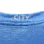 A camisa titular feminina do Manchester City 23/24 é azul celeste com faixas verticais em tom sobre tom, inspiradas nas torres do Etihad Stadium. Gola V branca com frisos azul celeste. Escudo do City e logos da PUMA em branco.