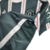 Camisa reserva Manchester United 23/24: Verde escuro com faixas verticais brancas e linhas vermelhas. Gola branca, três listras nos ombros em branco. Escudo Man United verde e branco, logo Adidas branco.