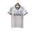 Reserva Napoli 2023-2024: branco com Vesúvio em marca d'água, gola V e detalhes em azul marinho nas mangas, logo EA7 e patrocínios também em azul marinho.