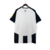 Camisa titular do Newcastle 2024-2025 Adidas com listras verticais preto e branco. Gola V preta, friso branco na nuca. Ombros e mangas pretos com listras brancas. Escudo NUFC, logo Adidas preto. Escudo antigo na nuca.