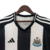 Camisa titular do Newcastle 2024-2025 Adidas com listras verticais preto e branco. Gola V preta, friso branco na nuca. Ombros e mangas pretos com listras brancas. Escudo NUFC, logo Adidas preto. Escudo antigo na nuca.