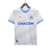 Camisa titular Olympique de Marseille 2023: branco com tons de cinza inspirados na rocha calcária, gola e punhos azul celeste com linha branca, logo PUMA dourado, escudo Marseille no lado esquerdo.