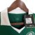 Camisa titular feminina Palmeiras 2024: design clássico, verde predominante, gola pólo e punhos brancos. Três emblemas históricos celebram 110 anos do clube. PUMA estampa felino e patrocinador em dourado, escudo atual no lado esquerdo.