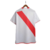 Camisa titular Peru 2023 Adidas. Camisa branca com faixa diagonal vermelha. Gola vermelha, listras nos ombros, punhos brancos com friso vermelho. Escudo seleção peruana e logo Adidas bordados.