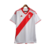 Camisa titular Peru 2023 Adidas. Camisa branca com faixa diagonal vermelha. Gola vermelha, listras nos ombros, punhos brancos com friso vermelho. Escudo seleção peruana e logo Adidas bordados.