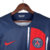 Nova camisa titular do PSG: azul marinho com faixa vertical deslocada, degradê branco. Gola redonda azul, escudo na faixa, logo Nike vermelho. Bandeira da França nas costas. 