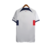 Camisa reserva PSG 2023-2024: predominante branca com faixa horizontal vermelho para azul marinho na barriga, gola e mangas em branco, escudo PSG, logo Nike em azul marinho e bandeira da França nas costas.