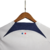 Camisa reserva PSG 2023-2024: predominante branca com faixa horizontal vermelho para azul marinho na barriga, gola e mangas em branco, escudo PSG, logo Nike em azul marinho e bandeira da França nas costas.