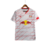 Camisa branca do Red Bull Bragantino com linhas vermelhas diagonais e horizontais, simbolizando dinamismo e energia. detalhes em vermelho nas mangas e escudo Massa Bruta e Logo New Balance em vermelho.