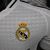 A nova camisa titular do Real Madrid versão jogador usa o template Teamgeist. Branca com padrão jacquard “Houndstooth”, gola V branca com friso preto na nuca. Logo da Adidas. Escudo Real Madrid na esquerda.