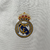 A nova camisa titular do Real Madrid usa o template Teamgeist. Branca com padrão jacquard “Houndstooth”, gola V branca com friso preto na nuca. Logo da Adidas. Escudo Real Madrid na esquerda.