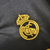 Nova camisa três do Real Madrid Feminina: preta, versátil e elegante. Três listras cinzas nas mangas, gola redonda com abertura de botão e iniciais RMCF costuradas em amarelo. Escudo amarelo e logo Adidas bodados.