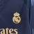 Camisa três do Real Madrid manga longa: preta, versátil e elegante. Três listras cinzas nas mangas, gola redonda com abertura de botão e iniciais RMCF costuradas em amarelo. Escudo amarelo e logo Adidas bodados.