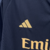 Camisa três do Real Madrid manga longa: preta, versátil e elegante. Três listras cinzas nas mangas, gola redonda com abertura de botão e iniciais RMCF costuradas em amarelo. Escudo amarelo e logo Adidas bodados.