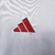 Camisa branca do River Plate com faixa diagonal vermelha. Detalhes em vermelho na gola V, três listras, punhos, laterais e barra. Escudo Millonarios na faixa à esquerda, logo Adidas vermelho à direita. 'Grandeza' na nuca .