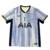 A nova camisa reserva dos Spurs 24/25 é azul clara com linhas verticais em vários tons de azul, inspirada no modelo de 92/94. A gola é V em azul marinho, cor das laterais. O escudo e logos são centralizados.