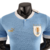 Camisa titular do Uruguai: azul celeste com design retrô. Gola V branca, abertura com botão. Tecnologia ULTRAWEAVE. Logo PUMA dourado nas mangas. Escudo AUF. 