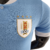 Camisa titular do Uruguai: azul celeste com design retrô. Gola V branca, abertura com botão. Tecnologia ULTRAWEAVE. Logo PUMA dourado nas mangas. Escudo AUF. 