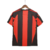 Camisa titular AC Milan 10/11 Adidas: vermelho e preto, com detalhes em dourado pela camisa. Dentro da gola, bandeira da Itália e escrito AC MILAN. Na nuca, bandeira italiana. Logo Adidas e escudo Milan bordados.